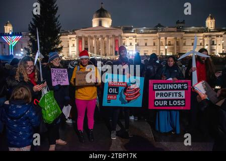 Les manifestants chantent des chants de Noël tout en brandissant des pancartes pendant la manifestation sur le Trafalgar Square à Londres. Les activistes de extinction Rebellion ont organisé une manifestation lors de la cérémonie officielle des lumières de Noël pour protester contre les plans d'Equinor, basé en Norvège, de développer le champ pétrolifère de Rosebank au Royaume-Uni. Banque D'Images