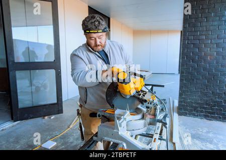 Trim Worker coupant les moulures en bois de base avec une scie à découper Banque D'Images