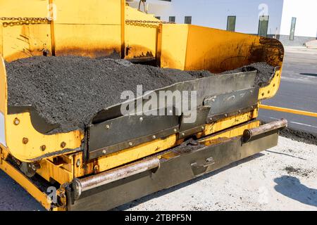 La construction de la route est effectuée par la machine de chaussée posant l'asphalte bitumineux de couche fraîche sur la base de gravier supérieure Banque D'Images