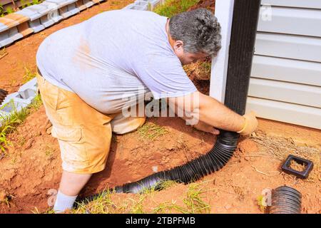 Installation de la goulotte de raccord pour tuyau de drainage d'extension de gouttière flexible avec écoulement de l'eau vers le bas Banque D'Images