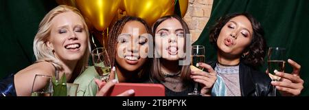 femmes multiethniques gaies avec champagne grimacant et prenant selfie sur téléphone portable dans le bar, bannière Banque D'Images