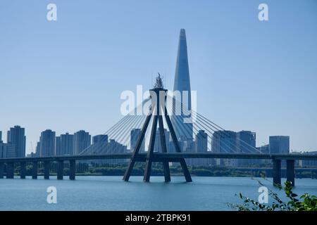 Ce panorama saisissant met en valeur l'imposante Tour Lotte et l'emblématique pont olympique enjambant la paisible rivière Han à Séoul. L'image capture le Banque D'Images