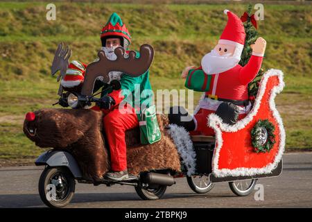 Père Noël sur un scooter Vespa décoré comme un renne et un traîneau, les membres du club de scooter Vespa RheinSchalter Koeln habillés comme Santas se rassemblent sur D. Banque D'Images