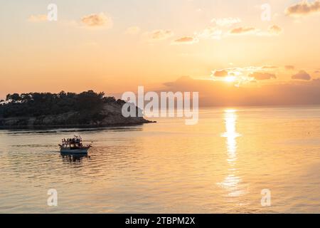 Une scène océanique tranquille avec deux petits bateaux amarrés au rivage lors d'un magnifique coucher de soleil Banque D'Images