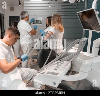 Consultation dentaire. Le médecin souligne les résultats de l'examen, les collègues médecins discutent du résultat de la radiographie et du scanner de la bouche Banque D'Images