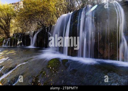 Un paysage magnifique avec une grande cascade descendant dans une rivière entourée d'arbres luxuriants dans un environnement naturel Banque D'Images
