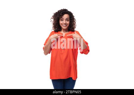 jeune femme brune bouclée vêtue d'un chemisier orange s'inspire d'une idée. concept de brainstorming Banque D'Images