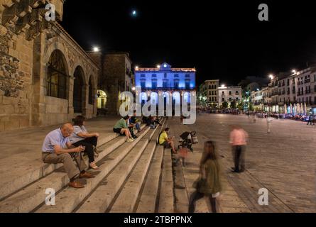Soirée à Caceres, Espagne. Touristes assis sur les escaliers de la place principale Banque D'Images