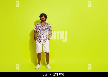 Photo pleine longueur de beau jeune homme posant mains poches porter vêtement imprimé léopard rose tendance isolé sur fond de couleur jaune Banque D'Images