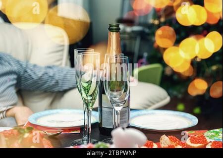 Réglage de table de Noël avec arbre de Noël en arrière-plan. La table est prête pour un dîner festif et la fête avec champagne et sandwichs avec ca Banque D'Images