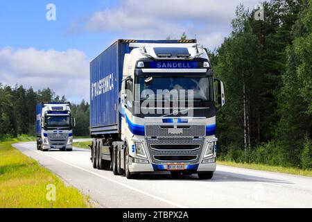 Deux semi-camions Volvo FH bleu blanc de Kuljetusliike H Sandell Oy transportant des conteneurs de fret le long de l'autoroute 25. Raasepori, Finlande. 7 juillet 2023. Banque D'Images