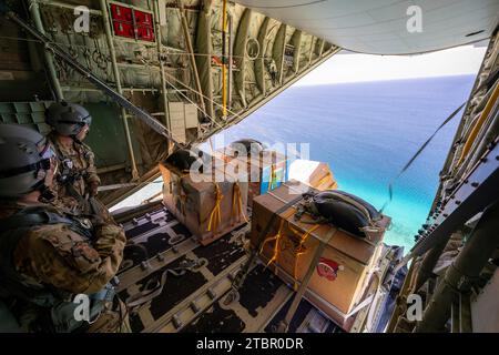 Atoll de Satawan, États fédérés de Micronésie. 05 décembre 2023. L'aviateur principal de l'US Air Force Joseph Snell, à gauche, et le sergent-chef Matthew Muravez, du 36th Expeditionary Airlift Squadron, poussent des paquets humanitaires hors d'un avion C-130J Super Hercules de l'US Air Force lors de l'opération Christmas Drop, le 5 décembre 2023 dans l'atoll de Satawan, en Micronésie. L’opération Christmas Drop est la plus ancienne mission humanitaire et de secours en cas de catastrophe qui fournit 71 000 livres de nourriture, de cadeaux et de fournitures pour aider les communautés insulaires éloignées du Pacifique Sud. Crédit : Yasuo Osakabe/US Airforce photo/Alamy Live Banque D'Images