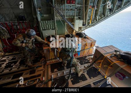 Atoll de Satawan, États fédérés de Micronésie. 05 décembre 2023. L'aviateur principal de l'US Air Force Joseph Snell, à gauche, et le sergent-chef Matthew Muravez, 36th Expeditionary Airlift Squadron, les maîtres de chargement se préparent à pousser un paquet humanitaire hors d'un avion C-130J Super Hercules de l'US Air Force lors de l'opération Christmas Drop, le 5 décembre 2023 dans l'atoll de Satawan, en Micronésie. L’opération Christmas Drop est la plus ancienne mission humanitaire et de secours en cas de catastrophe qui fournit 71 000 livres de nourriture, de cadeaux et de fournitures pour aider les communautés insulaires éloignées du Pacifique Sud. Crédit : Yasuo Osakabe/US Airforce photo Banque D'Images