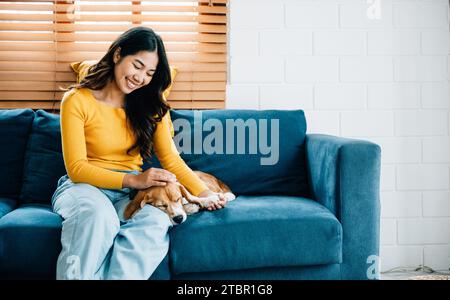 Une femme joyeuse, vêtue de sa combinaison exclusive, profite de moments ludiques avec son mignon chien Beagle Banque D'Images