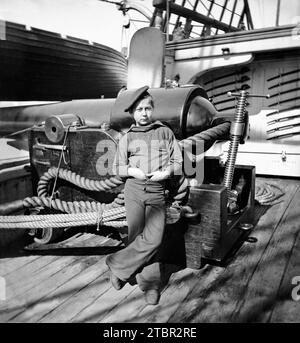 Un «singe poudrier» avec ses mains rentrées dans son pantalon debout à l'aise devant un grand pistolet à bord de l'U. S. Steamer Pawnee, vers 1864-65. Cutlas Banque D'Images