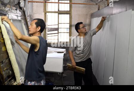 (231208) -- JINGXIAN, 8 déc. 2023 (Xinhua) -- Wu Fan (à droite) sèche du papier dans un atelier de papier Xuan dans le comté de Jingxian, dans la province d'Anhui, dans l'est de la Chine, le 7 décembre 2023. Le papier Xuan, un type de papier fait à la main, a été produit à l'origine dans la Chine ancienne et utilisé pour la calligraphie chinoise et les peintures. La procédure de fabrication du papier Xuan a été classée patrimoine culturel mondial immatériel par l'UNESCO en 2009. Jingxian, un comté sous la ville de Xuancheng dans la province d'Anhui, est l'endroit même où le papier Xuan a été inventé. Guan Jiaming, qui est en charge du processus de moulage du papier dans un atelier de papier Xuan, ha Banque D'Images