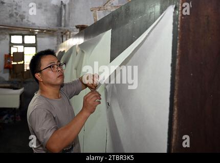 (231208) -- JINGXIAN, 8 déc. 2023 (Xinhua) -- Wu Fan sèche du papier dans un atelier de papier Xuan dans le comté de Jingxian, dans la province d'Anhui, dans l'est de la Chine, le 6 décembre 2023. Le papier Xuan, un type de papier fait à la main, a été produit à l'origine dans la Chine ancienne et utilisé pour la calligraphie chinoise et les peintures. La procédure de fabrication du papier Xuan a été classée patrimoine culturel mondial immatériel par l'UNESCO en 2009. Jingxian, un comté sous la ville de Xuancheng dans la province d'Anhui, est l'endroit même où le papier Xuan a été inventé. Guan Jiaming, qui est en charge du processus de moulage du papier dans un atelier de papier Xuan, a pr Banque D'Images