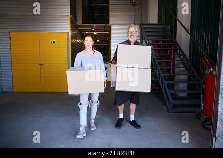 Un homme et une femme portent des boîtes en carton avec des choses Banque D'Images