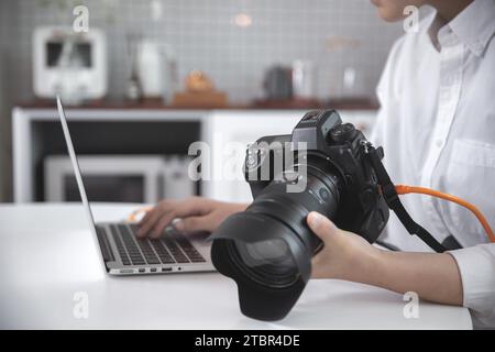 Femme photographe, blogueuse examinant des photos prises avec son appareil photo à l'aide d'un ordinateur portable Banque D'Images