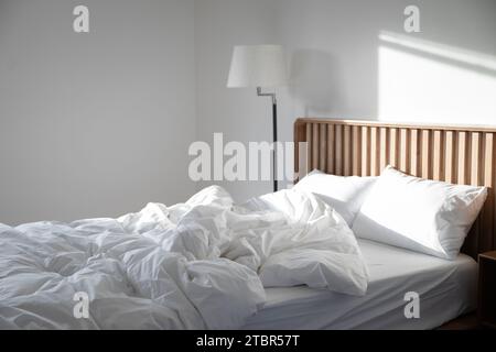 La lumière du soleil tombe sur une pièce vide avec une literie en désordre Banque D'Images