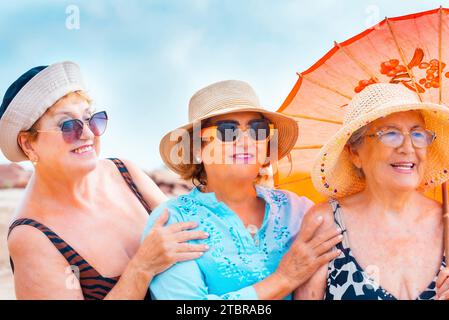 Groupe de femmes amies âgées souriant et posant pour une photo dans l'activité de loisirs de plein air d'été ensemble dans l'amitié. Accessoires colorés et lunettes de soleil. Vacances de vacances personnes âgées femmes dame Banque D'Images