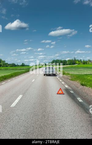 Panne de voiture sur une route de campagne avec triangle de signalisation sur l'épaule dure Banque D'Images