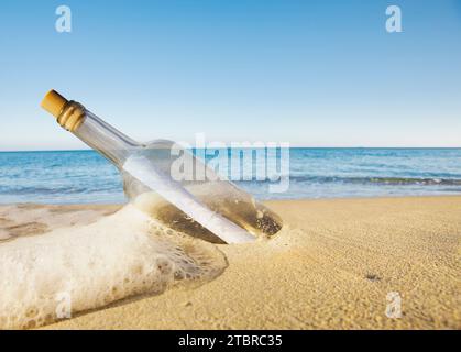 Message dans une bouteille sur la plage, emporté par une vague Banque D'Images