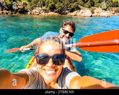 Heureux couple d'adultes actifs appréciant excursion en canoë kayak sur l'eau claire bleue transparente à la mer. Concept de bonheur homme et femme en vacances d'été. Mode de vie sain. Touriste Banque D'Images