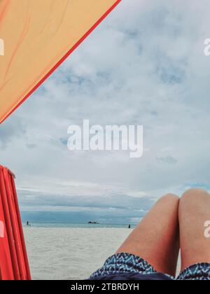 Allemagne, Mecklembourg-Poméranie occidentale, péninsule Fischland-Darß-Zingst, vue sur la plage de Prerow avec des nuages dans le ciel et l'humeur sombre, au premier plan jambes de femmes Banque D'Images