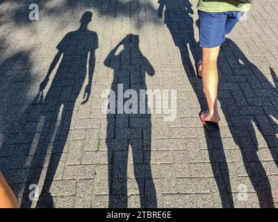 Les adolescents et les jeunes prennent des photos avec smartphone de leurs longues ombres dans la rue dans la lumière du soir d'été, Prerow, péninsule Fischland-Darß-Zingst, Mecklembourg-Poméranie occidentale, Allemagne Banque D'Images