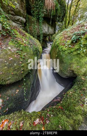 France, Bretagne, Huelgoat, Cascade le gouffre entre roches granitiques moussues dans la forêt d'automne de Huelgoat Banque D'Images