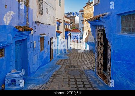 Ruelle étroite avec des murs bleus, des maisons et des portes dans la médina / vieille ville historique de la ville Chefchaouen / Chaouen, Maroc Banque D'Images