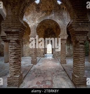 Arches et colonnes en briques anciennes dans un bâtiment historique avec des motifs uniques de filtrage de la lumière à travers le plafond. Banque D'Images