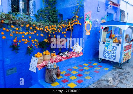 Chefchaouen, Maroc. 14 octobre 2022 - Street Juice stand à côté d'une maison pittoresque avec des plantes suspendues avec des oranges Banque D'Images