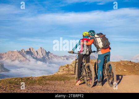 Italie, Vénétie, province de Belluno, Falcade, activités de plein air avec la famille, le père et la fille lors d'un tour en vélo électrique s'arrêtant pour admirer les montagnes au coucher du soleil Banque D'Images