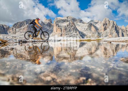 Italie, Vénétie, province de Belluno, Canale d'Agordo, cycliste faisant du VTT reflété dans un lac éphémère sur le plateau de Pale di San Martino, Dolomites Banque D'Images