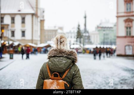 Femme va au marché de Noël pendant les vacances de l'Avent. Temps froid et blizzard neigeux en ville en hiver Banque D'Images