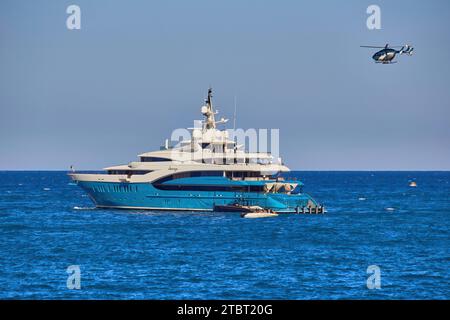 Rayons de soleil de superyacht de 85m à l'ancre avec l'hélicoptère entrant pour atterrir sur l'hélideck. Banque D'Images