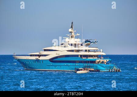 Rayons de soleil de superyacht de 85m à l'ancre avec l'hélicoptère entrant pour atterrir sur l'hélideck. Banque D'Images