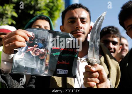 Sanaa, Yémen. 8 décembre 2023. Un manifestant tient un couteau et des photographies de Gaza, lors d’une manifestation de solidarité avec les Palestiniens dans le cadre du conflit en cours entre Israël et la Palestine. Les États-Unis ont imposé jeudi des sanctions à 13 individus et entités pour avoir prétendument acheminé des dizaines de millions de dollars en devises étrangères au groupe Houthi du Yémen de la vente et de l'expédition de marchandises iraniennes. (Image de crédit : © Osamah Yahya/ZUMA Press Wire) USAGE ÉDITORIAL SEULEMENT! Non destiné à UN USAGE commercial ! Crédit : ZUMA Press, Inc./Alamy Live News Banque D'Images