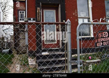 Abandonné Red Brick House derrière No Trespassing Chain Link Fence Banque D'Images