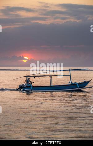 Paysage matinal pris sur une plage de sable, vue sur la mer à l'horizon avec de petits temples dans l'eau et un jukung, un bateau de pêche traditionnel dans la mer, lever du soleil à Sanur, Bali, Indonésie Banque D'Images