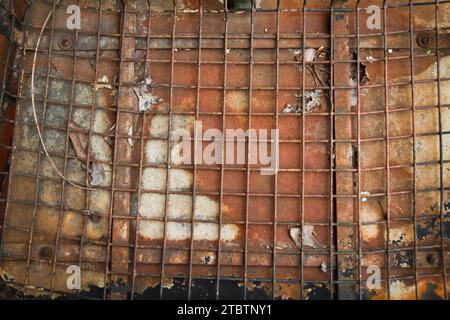 Grille rouillée et feuilles tombées sur une surface métallique altérée Banque D'Images