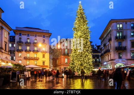 Vue imprenable sur le sapin de Noël de Lugano dans la nuit et les vieux bâtiments. Les gens de mouvement brouillé . Cafés en plein air sur la place Banque D'Images