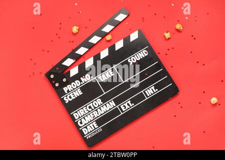 clapper de film avec pop-corn et confettis sur fond rouge. Fête de la Saint-Valentin Banque D'Images