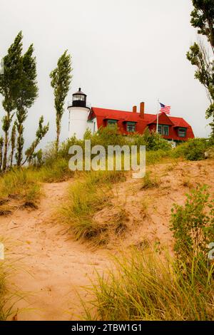 Phare blanc classique avec toit rouge sous ciel couvert dans les dunes de sable Banque D'Images
