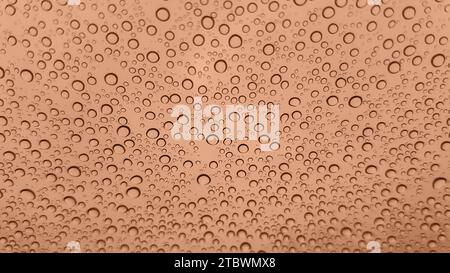 Image abstraite de gouttes de pluie sur verre. Image teintée dans la couleur Peach Fuzz de l'année 2024. Nouvelle couleur mode. Vue de dessus. Vue DROPs abstraite Banque D'Images