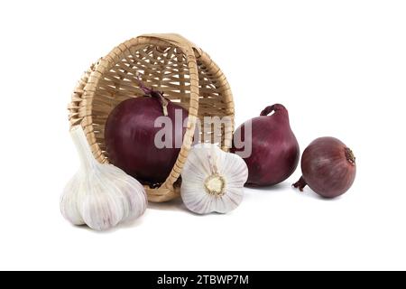Les oignons rouges et les bulbes d'ail sortent du panier en osier sur fond blanc Banque D'Images