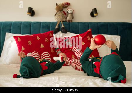 Bébé fille et tout-petit habillé comme des elfes jouant sur un lit Banque D'Images