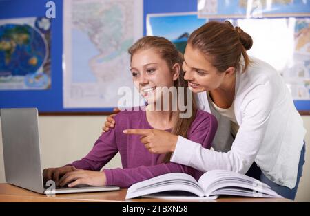 Enseignant, étudiant et ordinateur portable en classe pour l'éducation, l'apprentissage et la recherche avec des livres de géographie ou de bourses. Fille heureuse et femme tapant dessus Banque D'Images